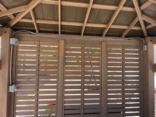 A wooden pergola with new wiring along the beams
