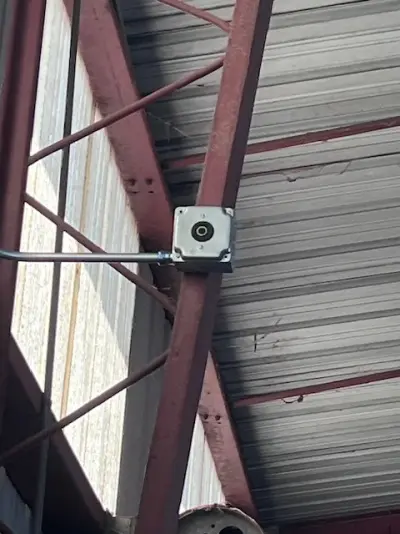 A new outlet box mounted on a red steel beam inside a shop