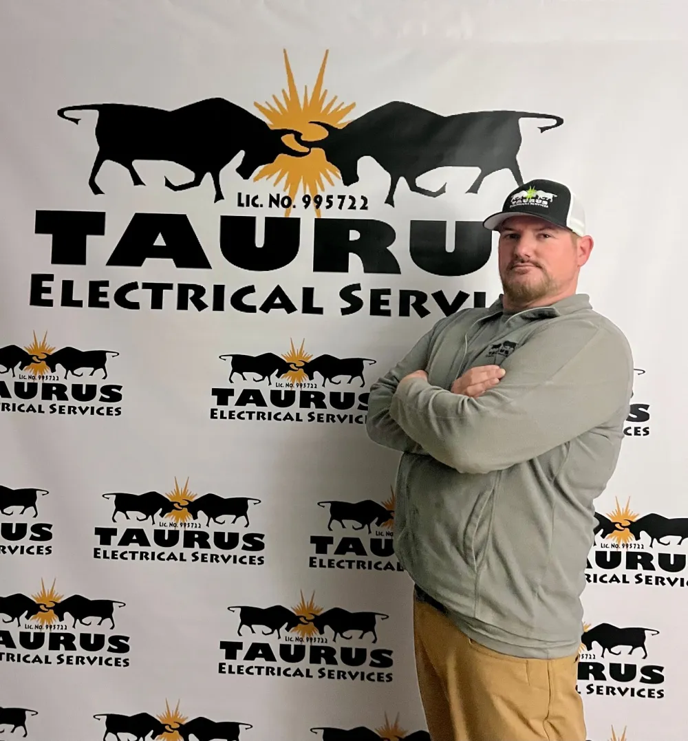 Steve Pritchard, owner of Taurus Electrical Services, arms folded in front of a Taurus logo backdrop